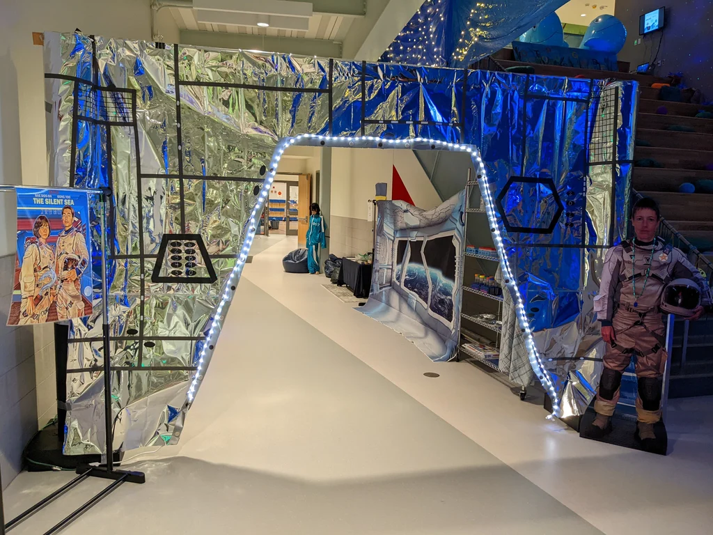 Space theme party with man as astronaut standing in front of a door displaying a sign